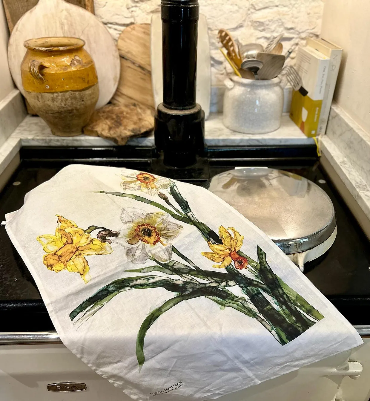 Jessica Trotman watercolour daffodil tea towel in yellow and white, printed on white linen and draped over a cream AGA